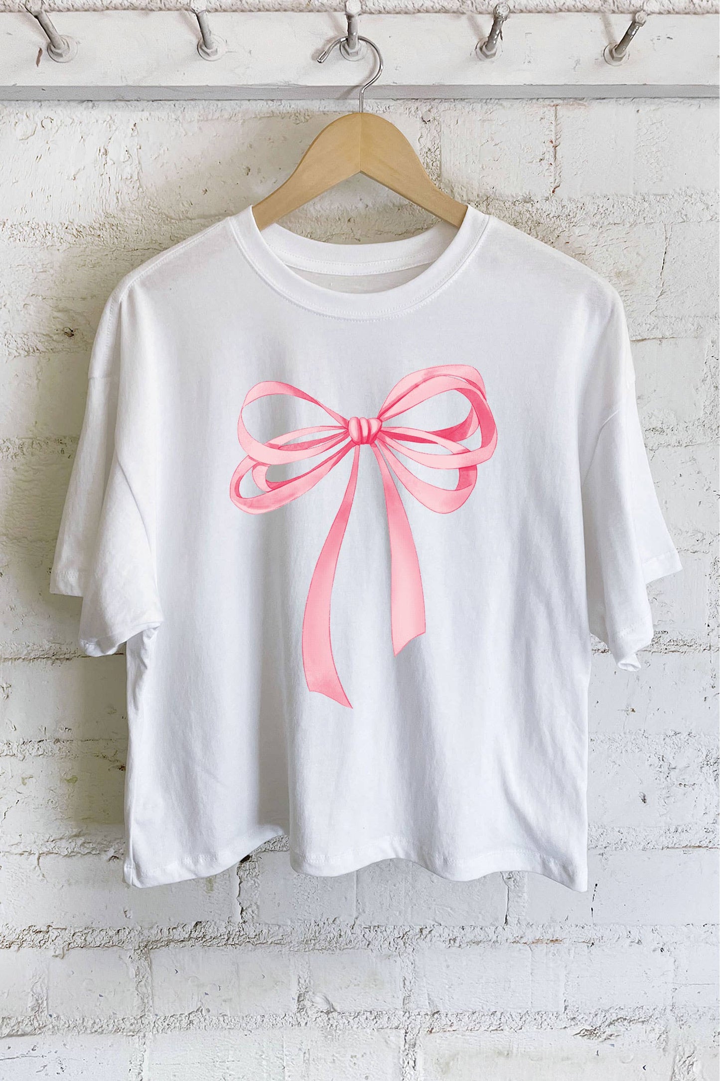 Introducing the COQUETTE Pink Bow Crop Top. Made with soft cotton fabric, this relaxed and boxy fit tee features a classic crew neckline and a unique pink bow graphic. Its slightly cropped fit adds a modern twist to this timeless piece. Perfect for adding a touch of femininity to any outfit.